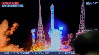 a rocket lifting off amid towers with darkness in the background. it's a tv view of the launch with Korean Hangul characters describing the scene in front