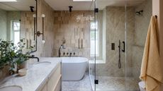 A neutral bathroom with wall tiles, a wooden vanity, and a glass shower screen