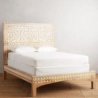 Handcarved Albaron Bed against a gray wall.