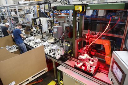 Man and machine working side by side at a factory.