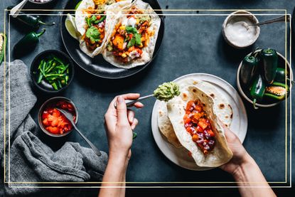 An aerial view of someone filling a soft shell taco