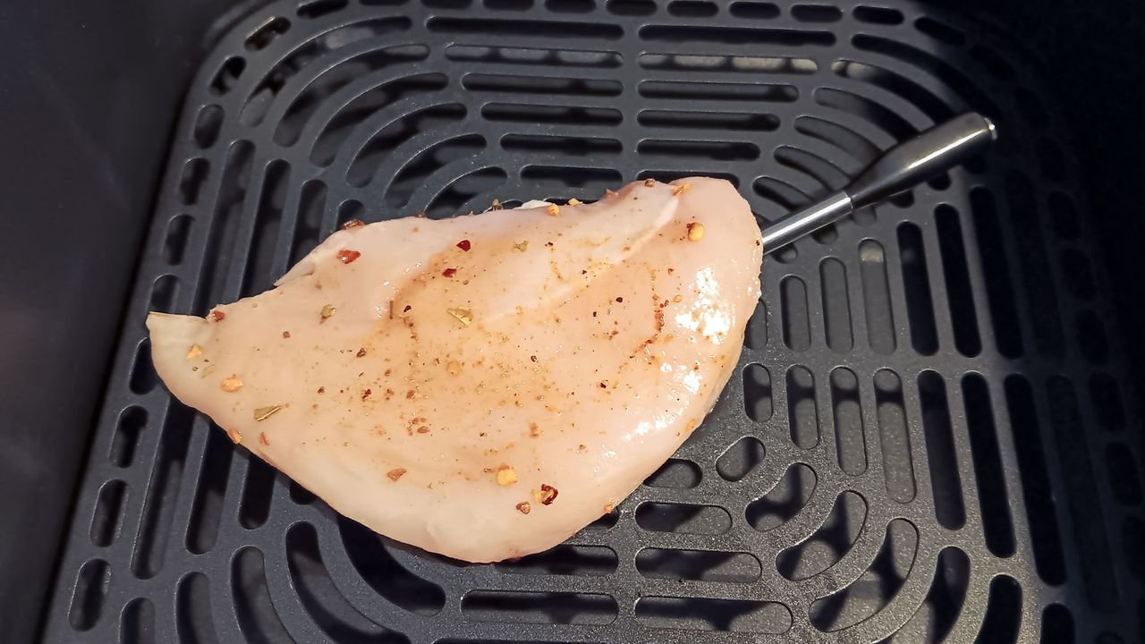 Raw chicken breast inserted with Cosori smart meat thermometer probe