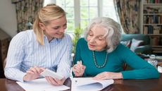 A young woman helps an older woman with her paperwork.
