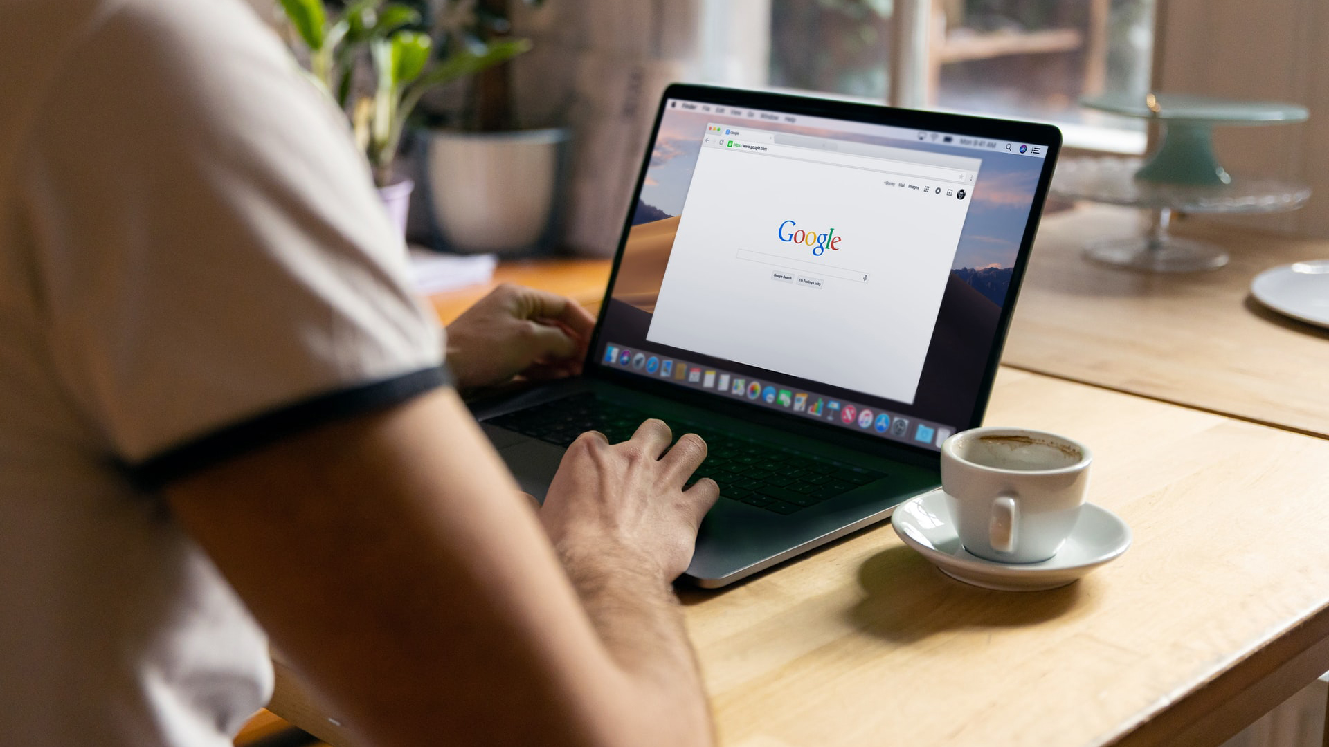 A person at a desk on a laptop accessing Google