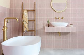 Pink tiling with white grout in bathroom complete with slate gray floor, white tub and gilded accents througout