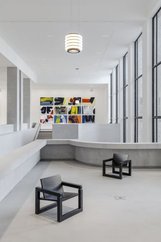 Seating area with two black wooden chairs and collage art on the wall