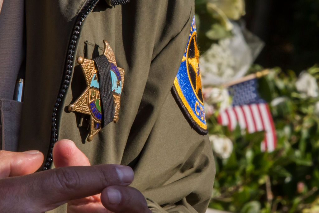 Police officer&amp;#039;s badge with mourning strip, in front of the Borderline Bar and Grill&amp;#039;s parking lot in Thousand Oaks, California on November 9, 2018.