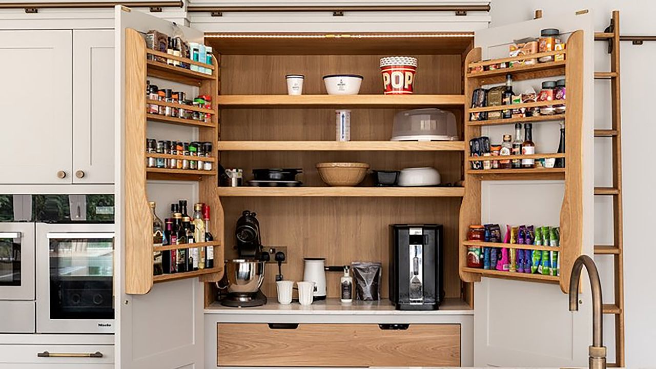 Pink kitchen with open double fronted pantry with wood interior.