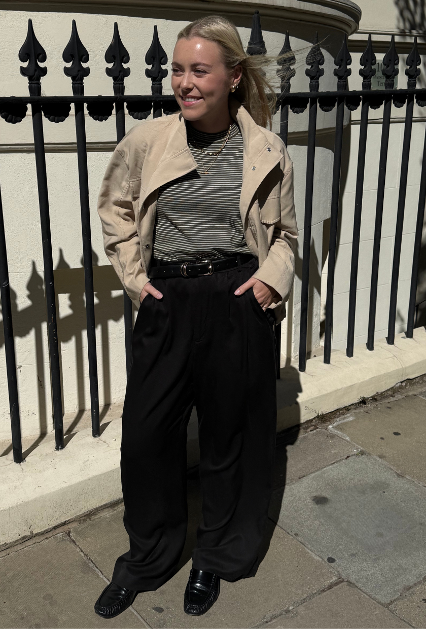An image of Who What Wear UK shopping editor Florrie Alexander wearing Reformation's Mason Trousers with loafers, a stripe top and biege jacket.