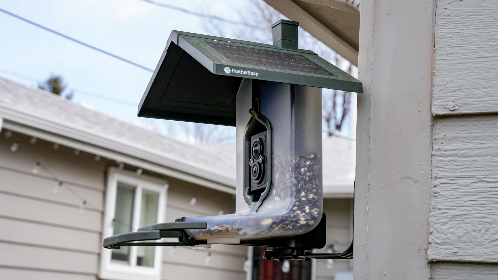 Feathersnap Scout Bird Feeder mounted on the side of a house.