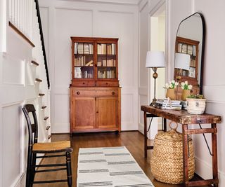 entryway with white walls patterned runner and traditional dresser