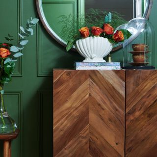 green wall with white shell on wooden cabinet with roses
