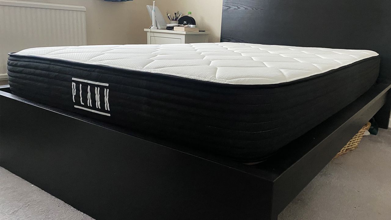 The Plank Firm Mattress (with the Extra Firm side facing upwards) on a black bed frame in our reviewer's bedroom