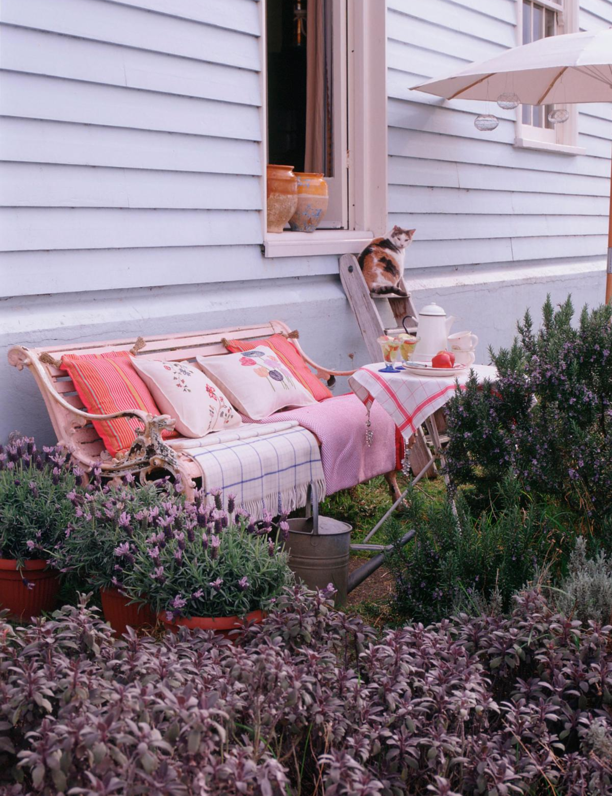 Charming garden bench vignette styled with throw pillows and blankets just before sunset
