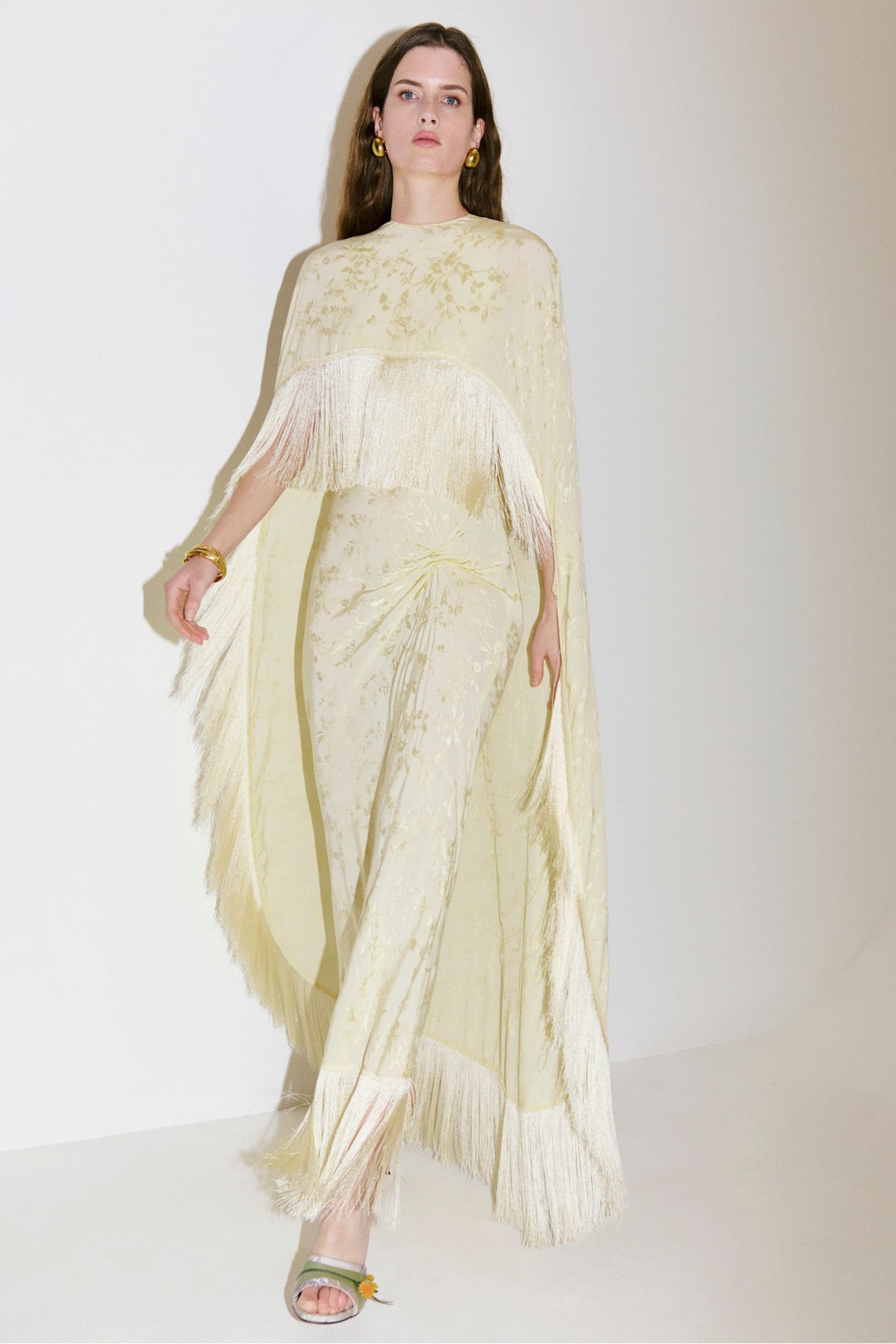 A model wearing a cape fringe dress from Anna October's Pre-Fall 2026 collection.