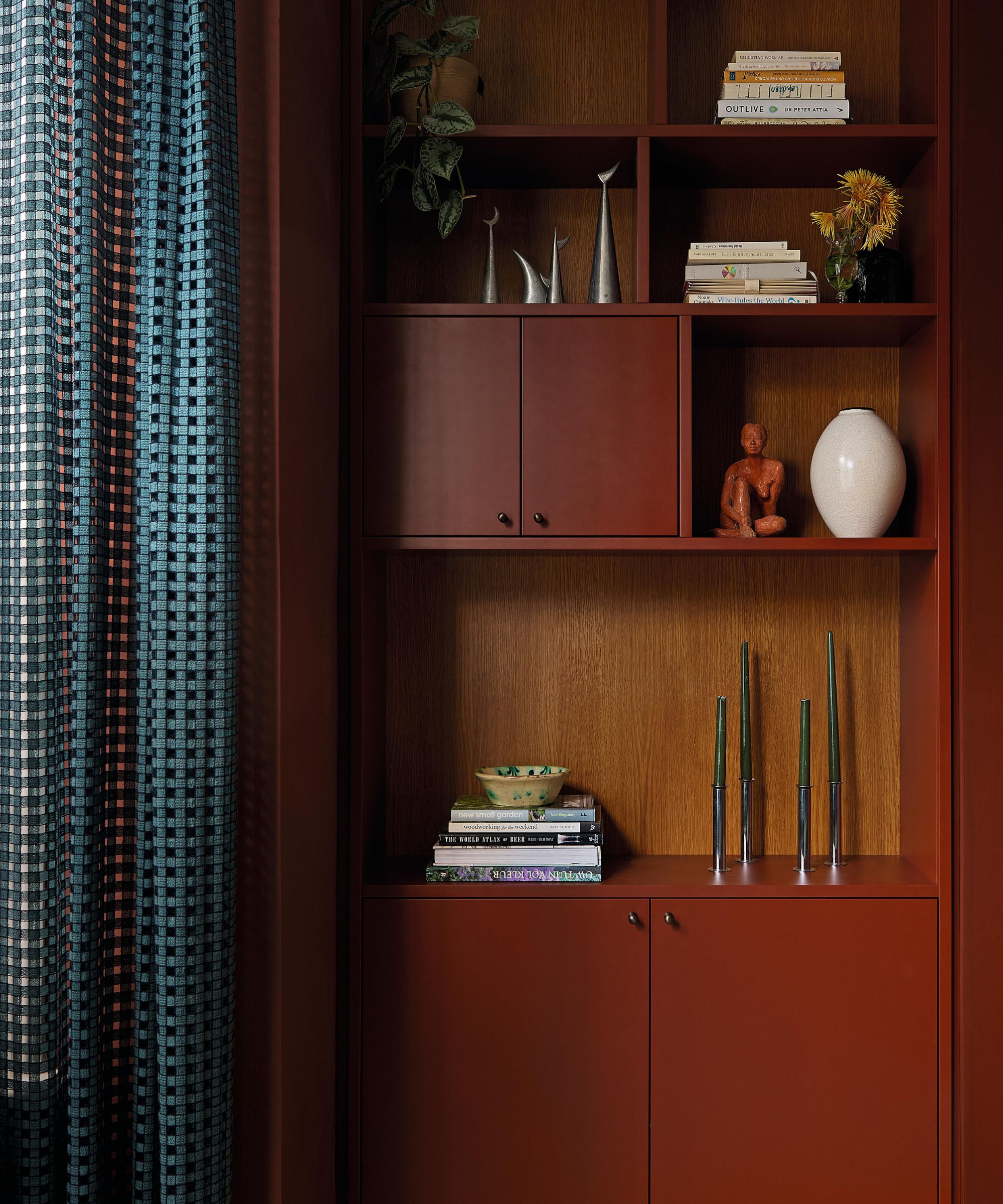 a london living room with dark red alcove units and blue sheer drapes at the window