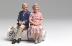 Reduce your tax bill: a retired couple sitting on roll of UK bank notes.