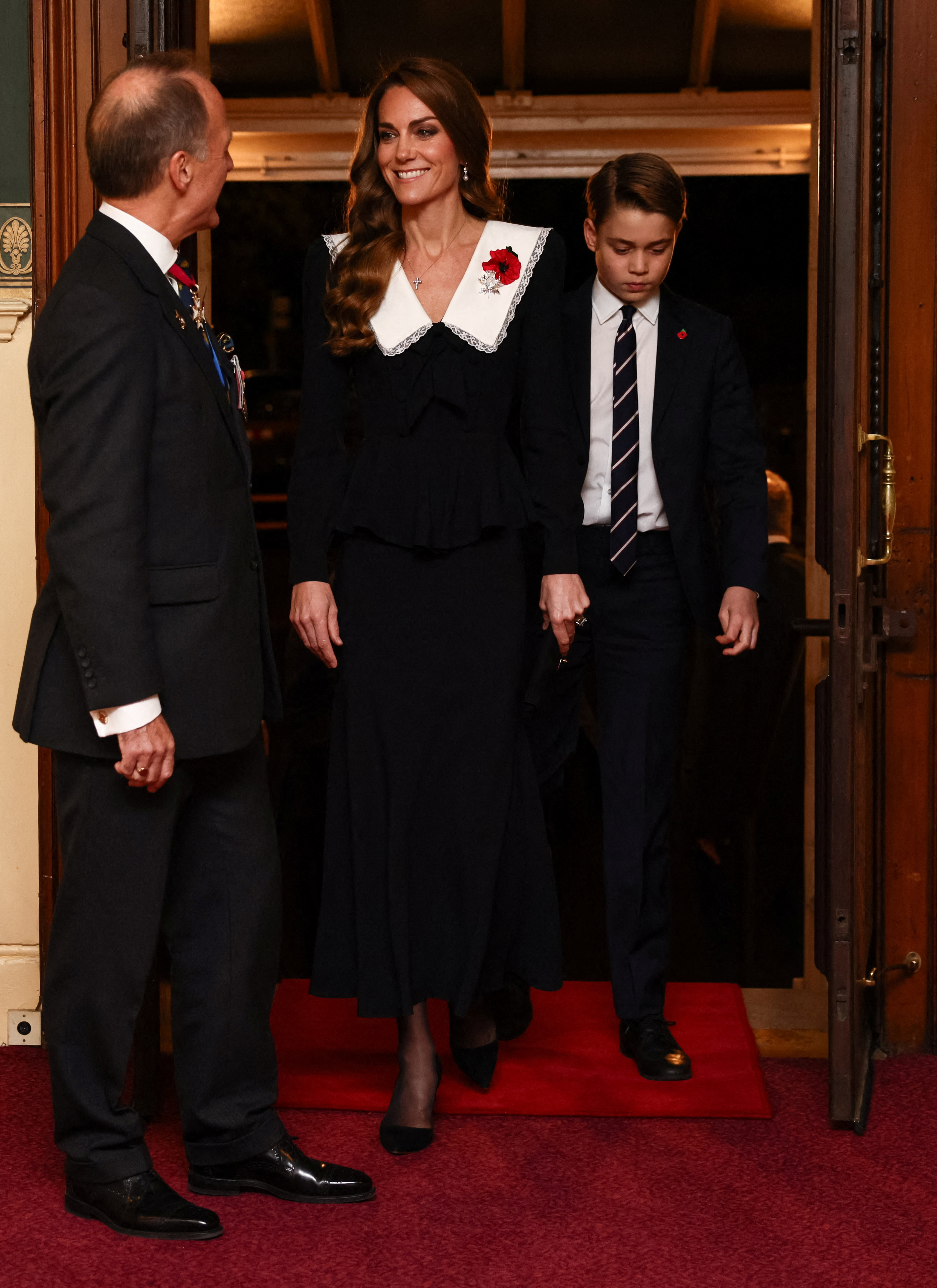 Kate Middleton wears a black dress with a large white collar and is accompanied by eldest son Prince George at the Royal British Legion Festival of Remembrance at the Royal Albert Hall in London
