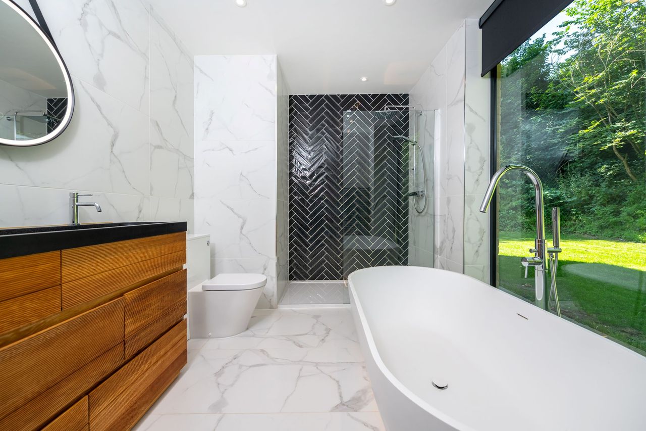 A white bathroom with a white bath as well as walk in shower