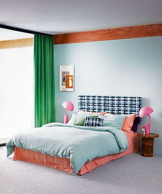 Modern bedroom with a double bed with green bed linen, pink bedside lamps and green curtains.