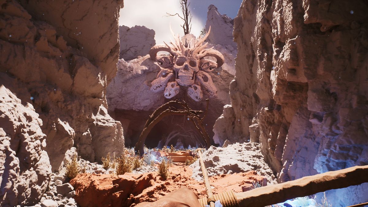 view down red clay canyon into a cave, massive skulls hanging over the entrance