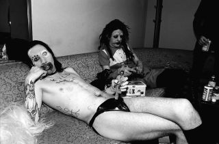 Marilyn Manson, left, and Twiggy Ramirez, right, relax on a couch backstage at the "Jon Stewart Show" in June 1995