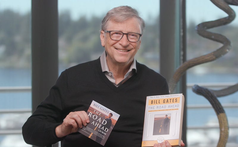 Bill Gates holding a copy of his book 