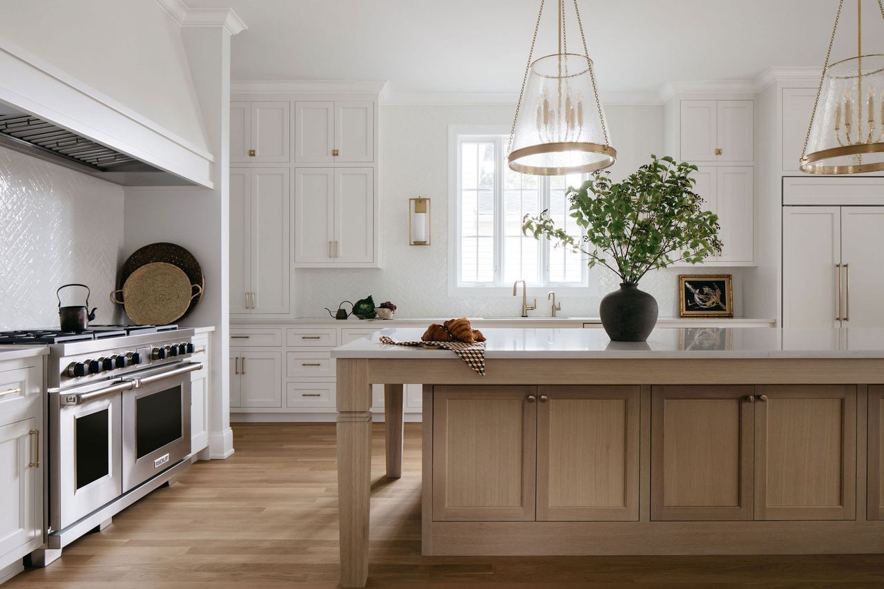 a white kitchen with wooden flooring and a wood island