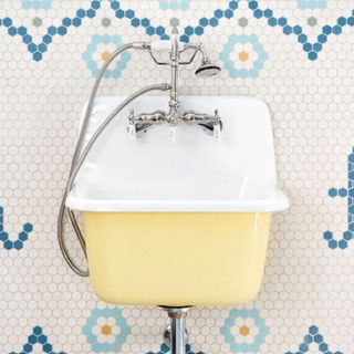 A yellow laundry sink on a tiled wall