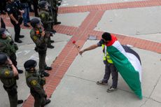 A pro-Palestinian demonstrator and police officers at the University of California at Irvine (UCI) on May 15, 2024