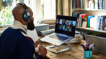 A man looks at his laptop screen while working in his home office.