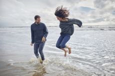 Carefree man and woman jumping in the sea
