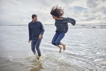 Carefree man and woman jumping in the sea