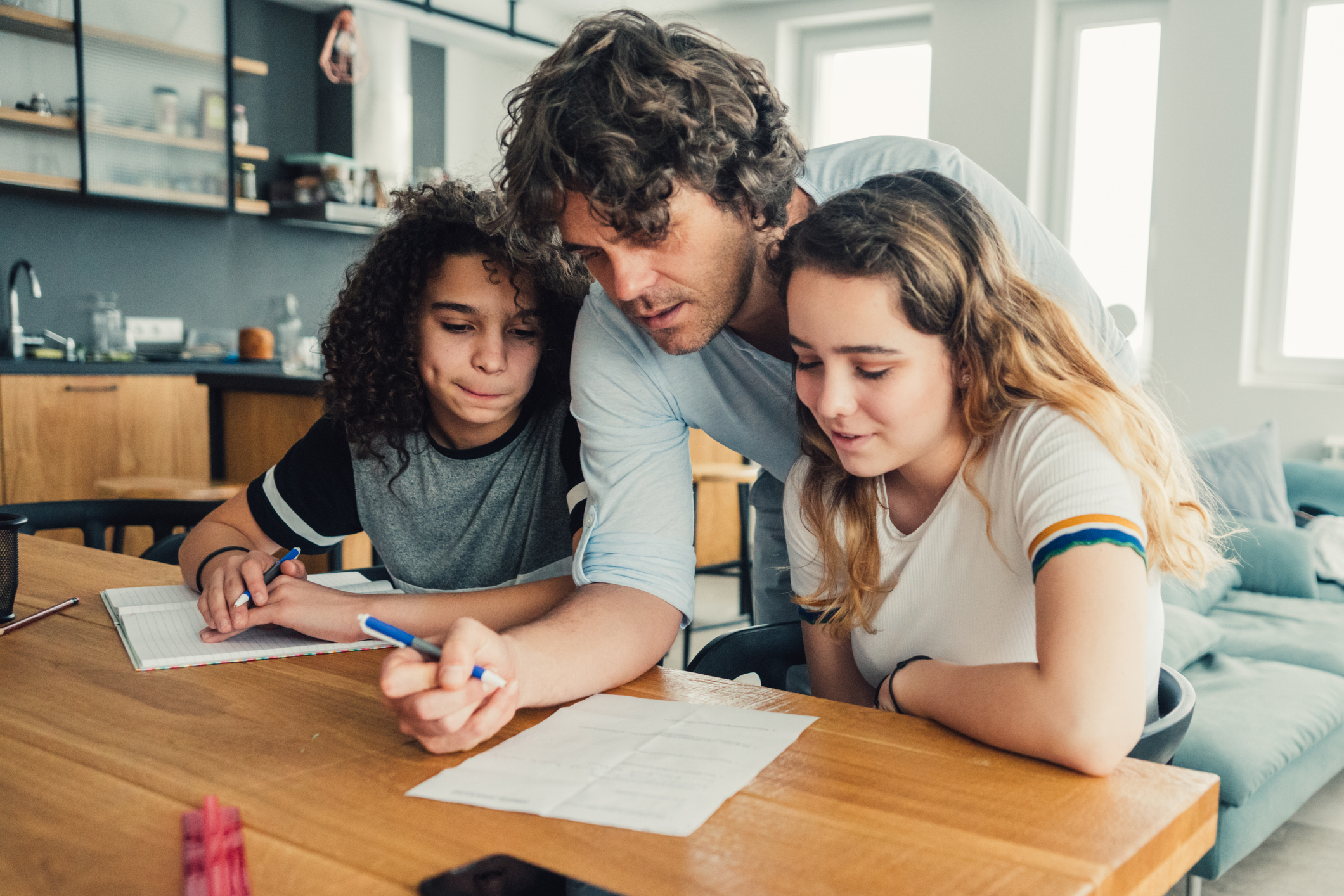 Father doing homework with his two children (daughter and son)