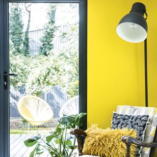 Living room with yellow feature wall and black floor lamp