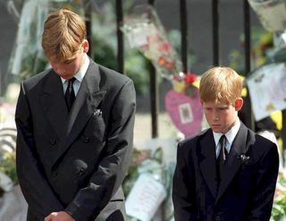 Prince William (left) and Prince Harry (right) with their head bowed at their mother's funeral