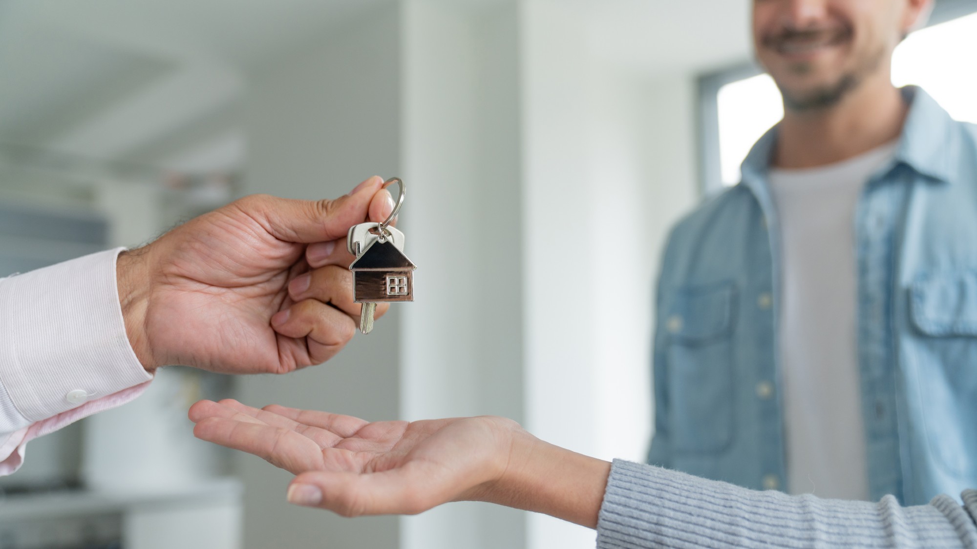 Real estate agent giving the keys of a house to a couple who just purchased it