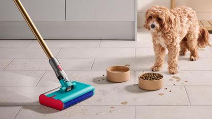A Dyson V15s Detect Submarine cordless vacuum and mop cleaning a tiled floor next to a dog