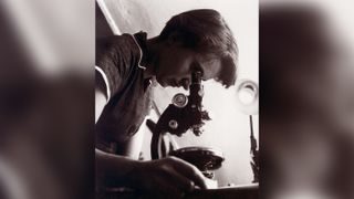 Photo of Rosalind Elsie Franklin looking through a microscope