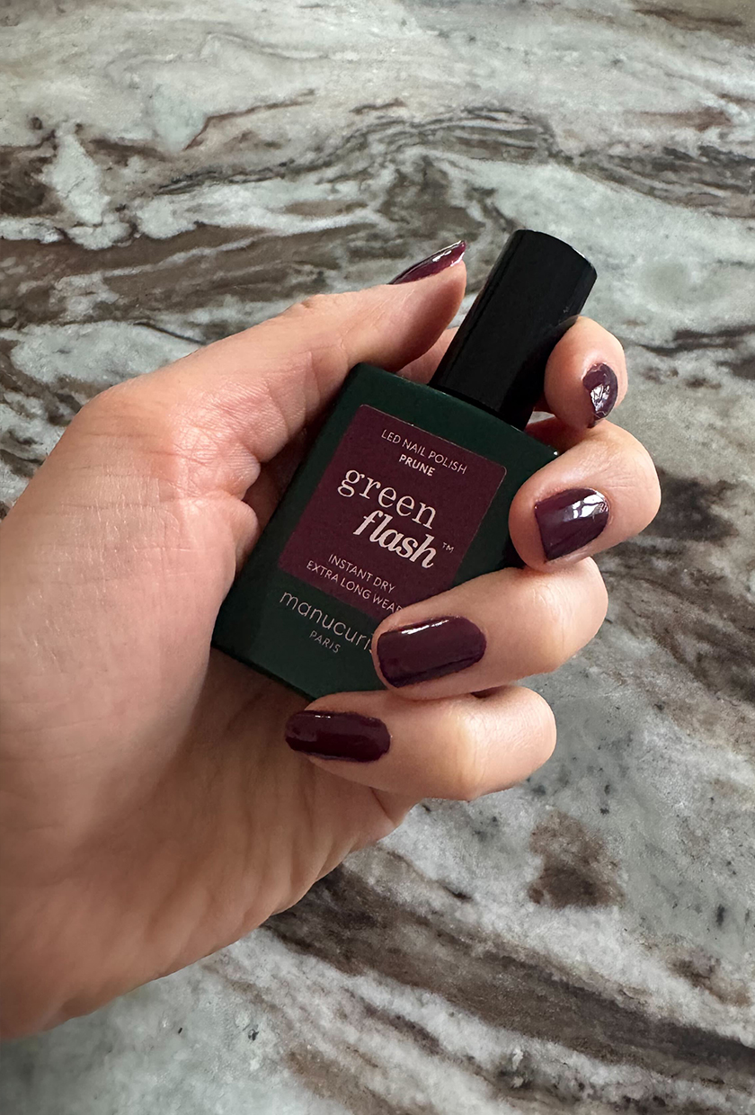 Eleanor holding and wearing the Manucurist Green Flash polish in Prune on her nails