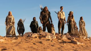 L-R: Lan (Daniel Henney), Rand (Josha Stradowski) and Moiraine (Rosamund Pike) stand on a sand dune surrounded by Aiel people in a scene from "The Wheel of Time" season 3