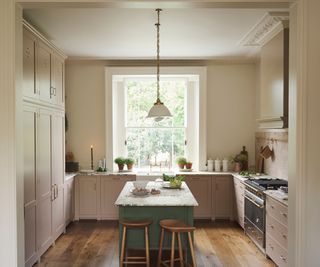 A pink kitchen with a green kitchen island