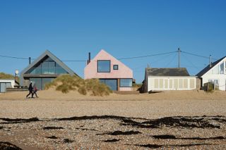 A shot of the pink home on the beach beside other homes