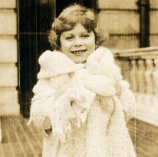 A black and white photo of Queen Elizabeth as a child wrapped up in a lace shawl