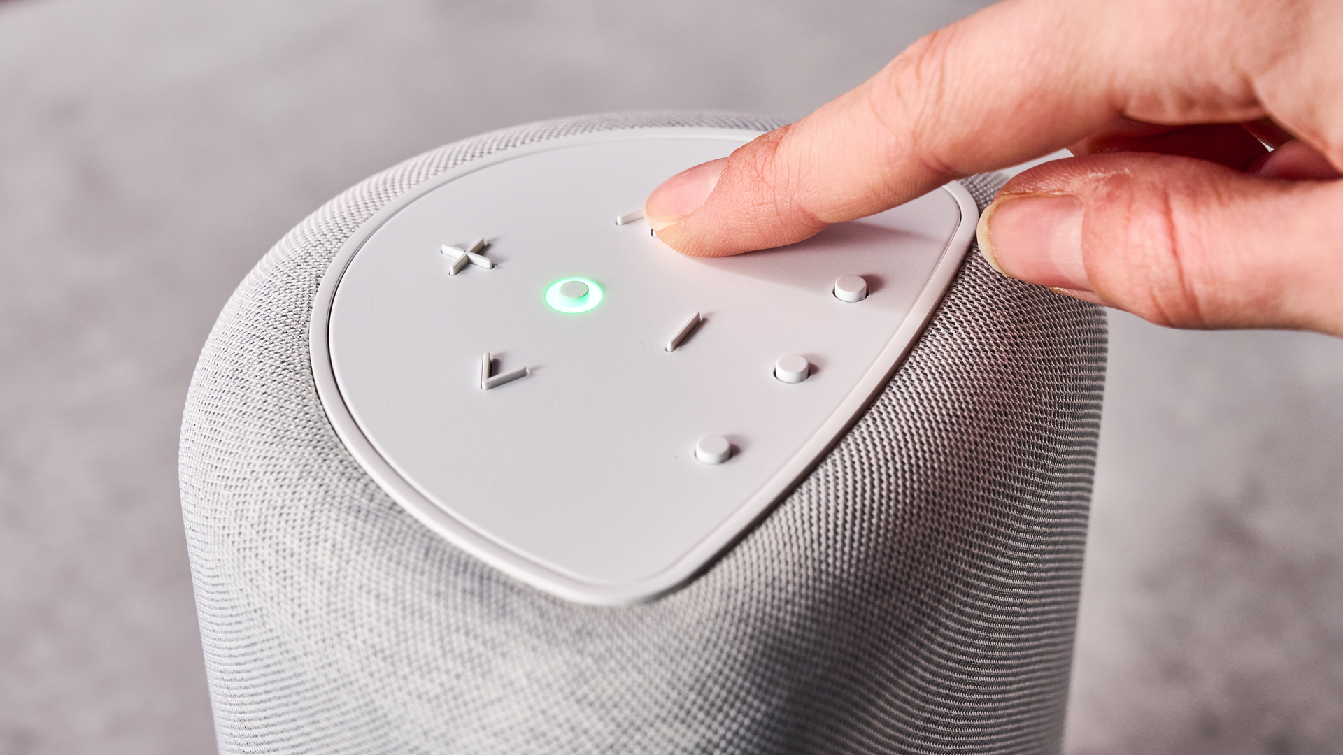 A woman's hand presses the skip forward button on the Bluesound Pulse Flex.