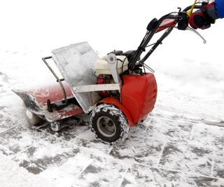 Snow blower on a paved pathway covered in snow
