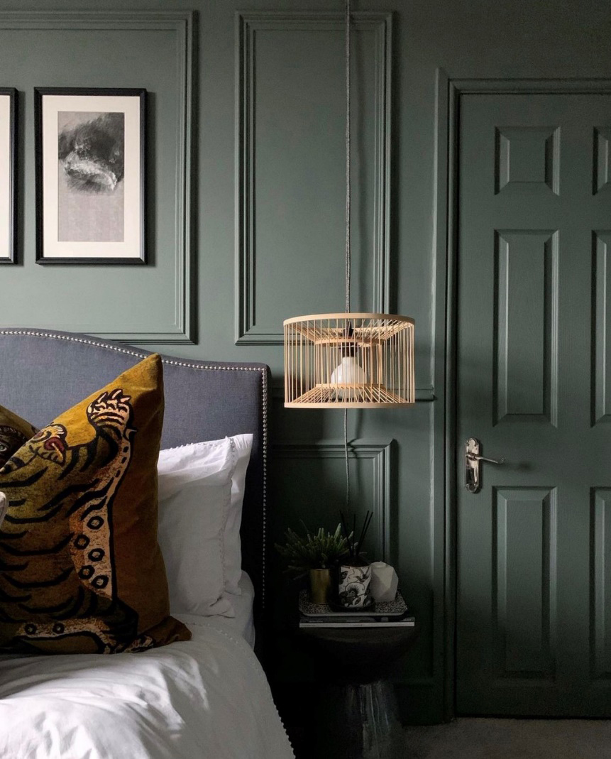 A green panelled bedroom with pendant side lamp and framed monochrome wall art