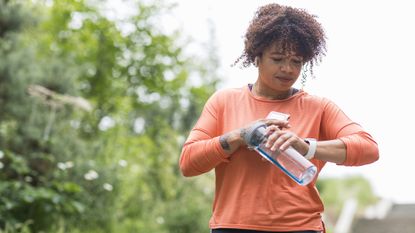 Does walking build muscle? Image shows woman walking and looking at fitness tracker on wrist