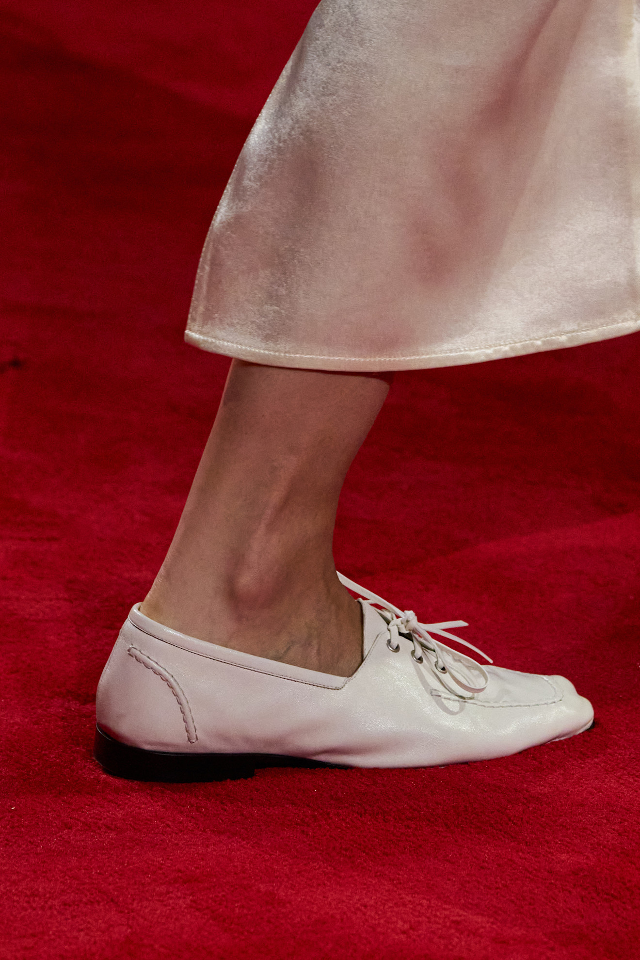 A close-up of a model walking in the Bottega Veneta F/W 26 show during Milan Fashion Week wearing white lace-up loafers.