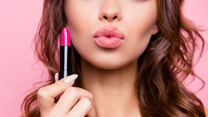 Pouting woman holding a stick of lipstick 